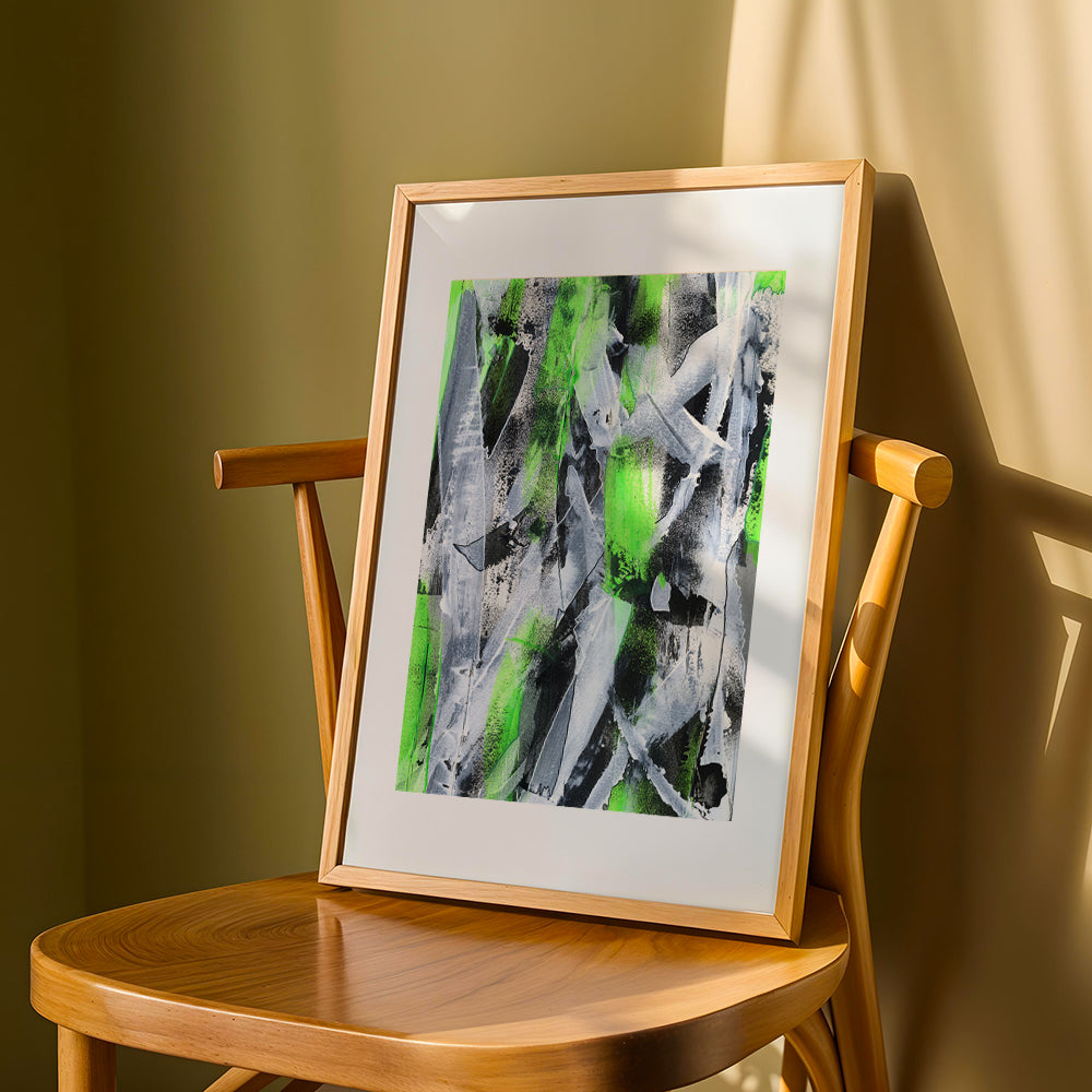 a green abstract original paper in a wooden frame propped up on a chair against a yellow mustard wall