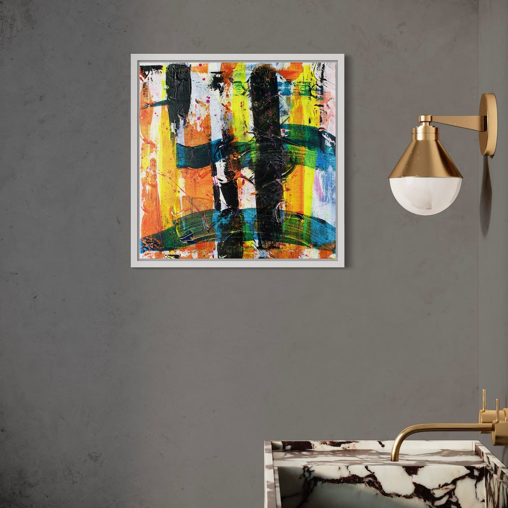 a multi-coloured abstract canvas original in a white frame styled on a dark grey wall in a bathroom next to a washstand