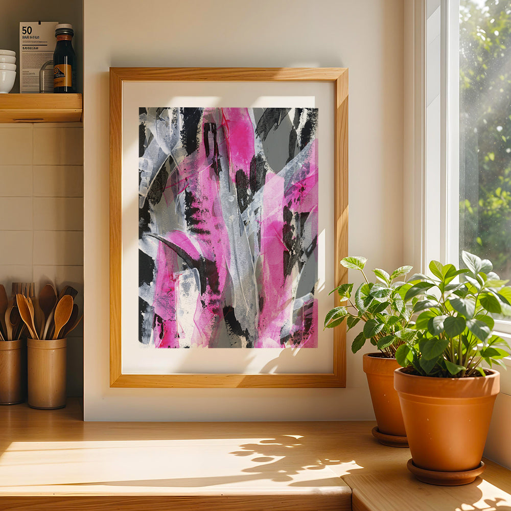 A pink abstract original on paper in a natural wood frame styled on a sunny wall in a kitchen next to a window and a plant pot