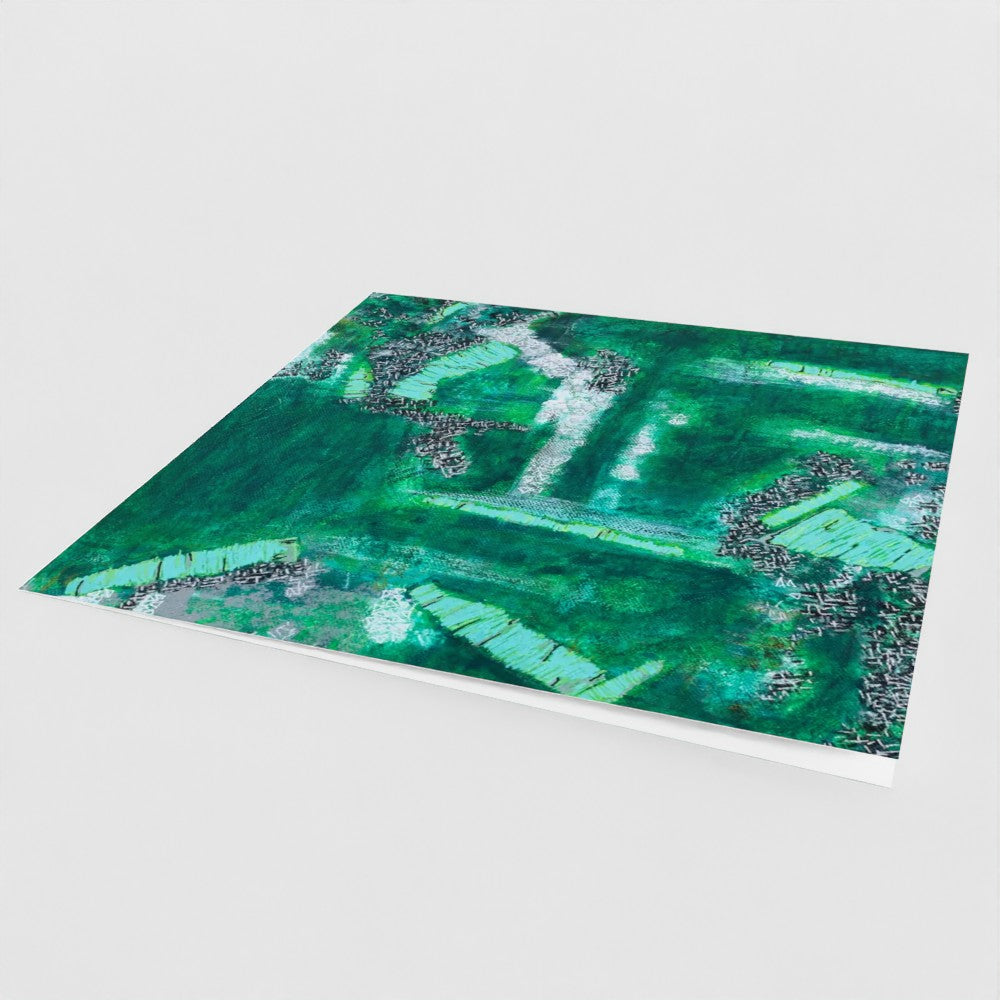 the front cover, at an angle, of a green square greeting card with an abstract design