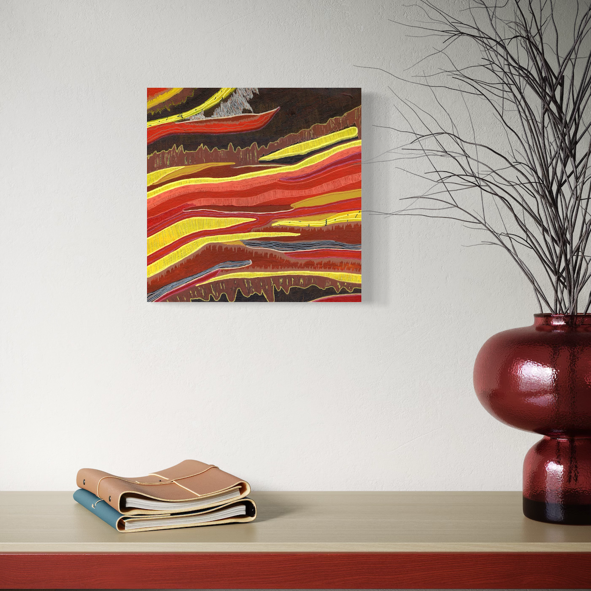 Abstract painting with red, yellow, and brown colors on a white wall above a wooden shelf with books and a vase.