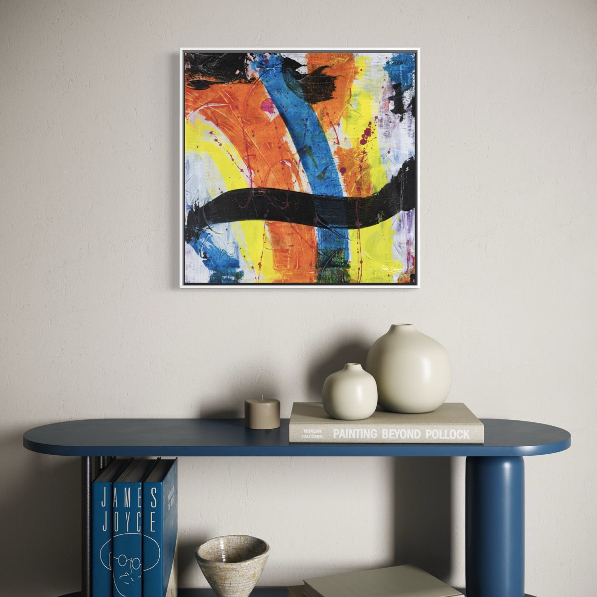 a multi-coloured original abstract canvas in a white frame styled on a light wall above a blue table with a few clay pots