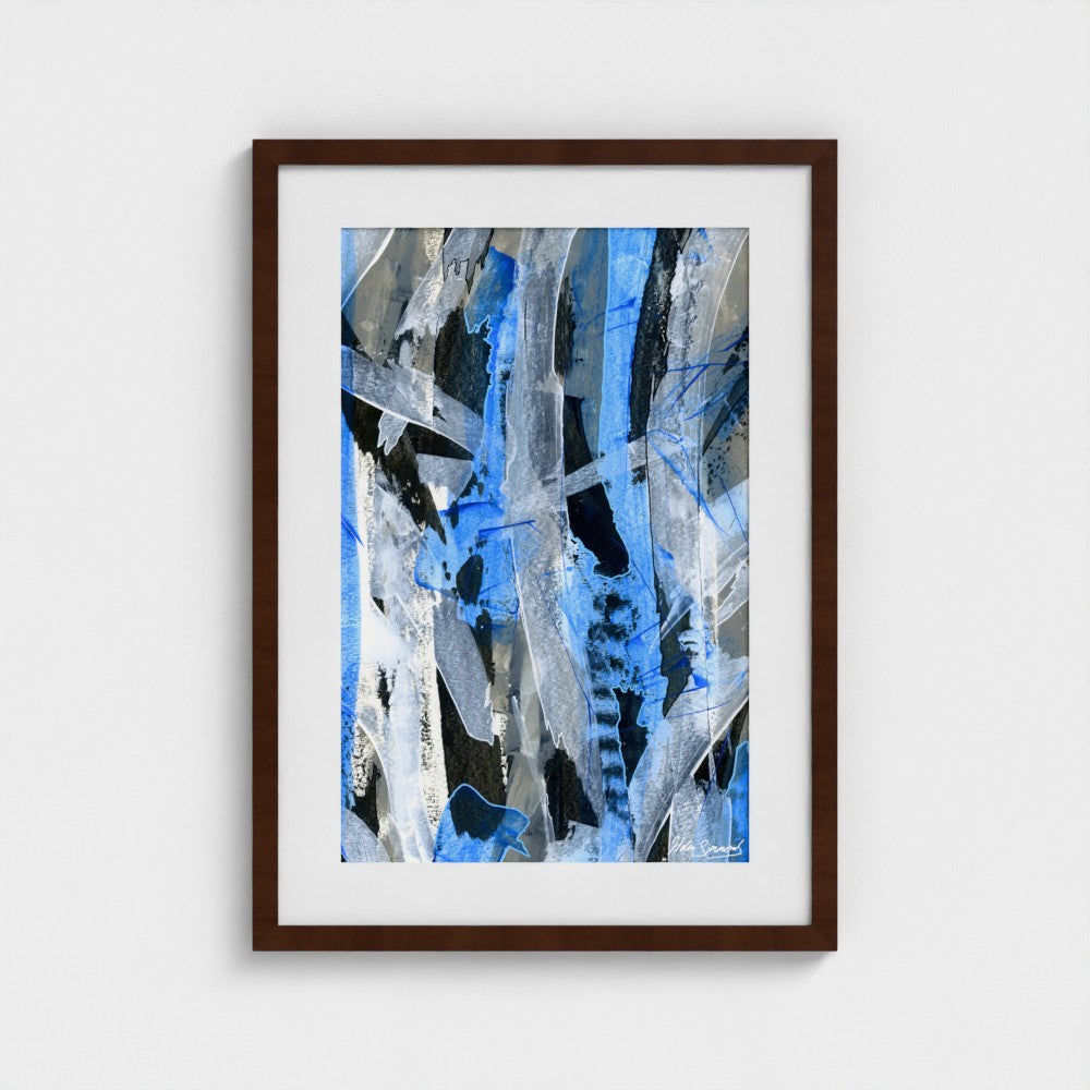 A blue abstract paper art print in a dark brown frame styled on a light wall