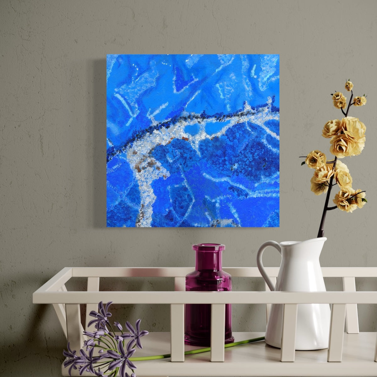 Abstract blue painting on a wall above a white shelf with decorative items.