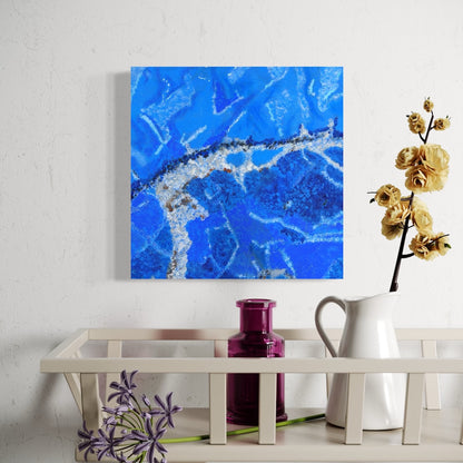 Abstract blue painting on a white wall with decorative items below.