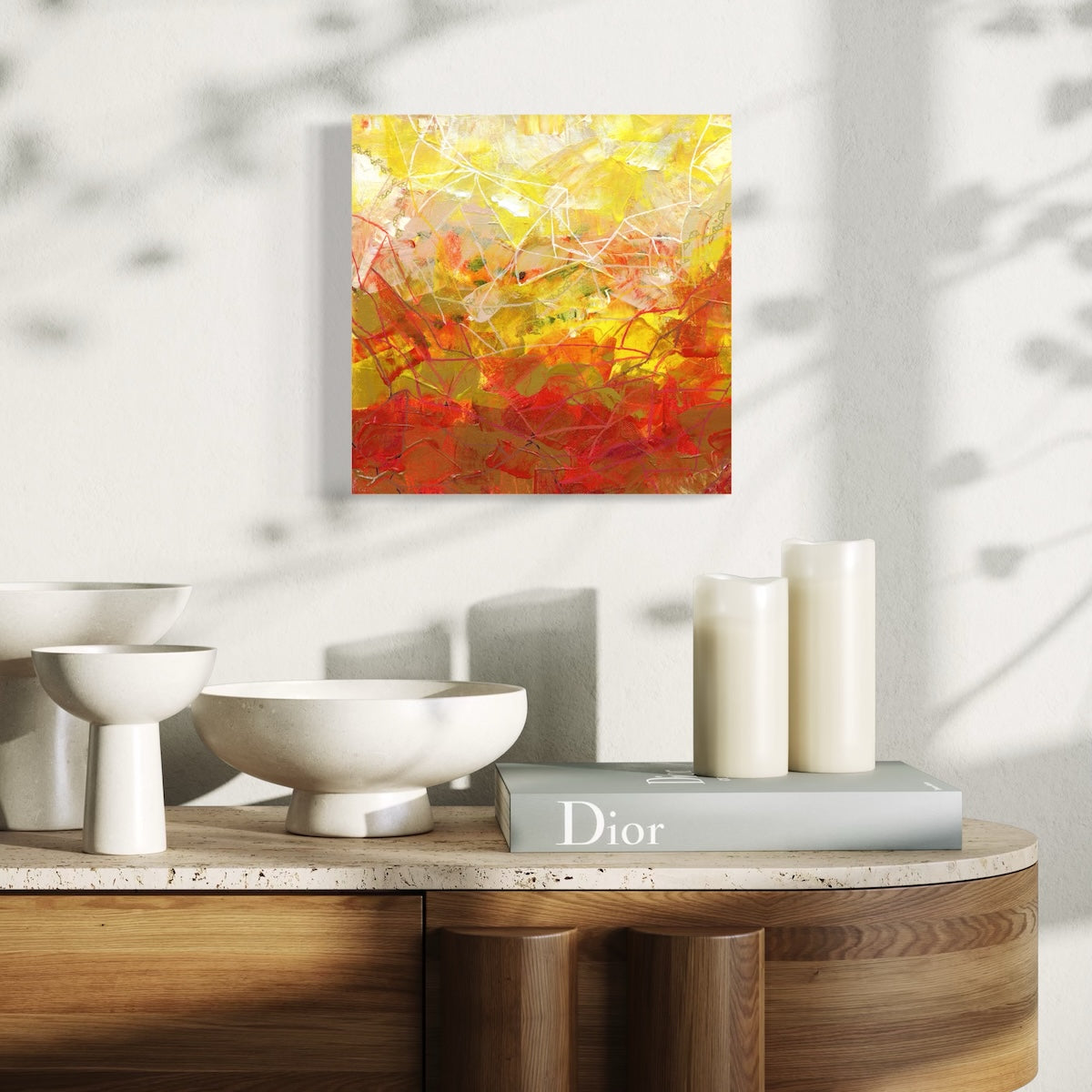 a yellow abstract original canvas styled on a light wall above a wooden table with candles