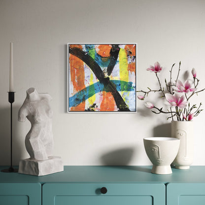 a multi-coloured abstract canvas painting in a white frame styled on a light wall above a light blue dresser with a torso statue and a pot of pink flowers.